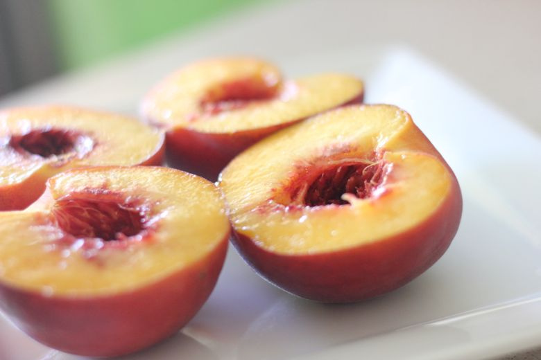 Peaches sliced in half and pit removed on a plate. 