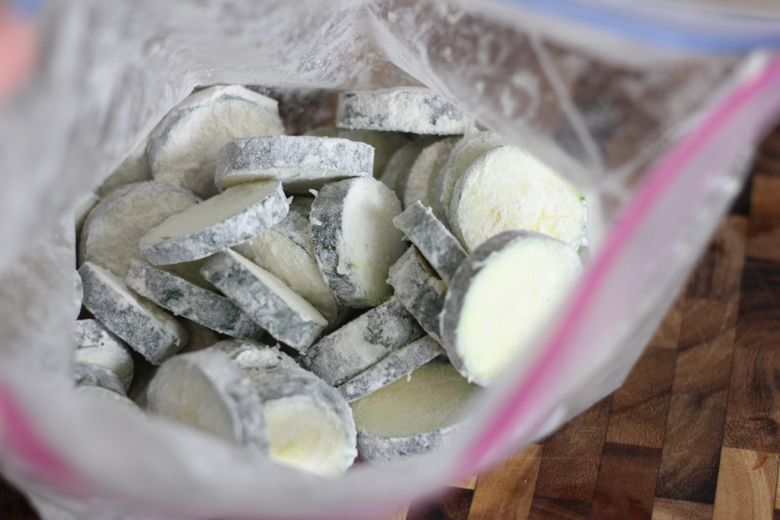 Zucchini slices coated in flour in a Ziploc bag.  