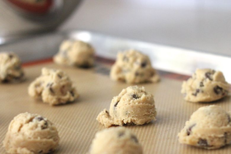 Emilee's Chocolate Chip Cookie dough scoops on a Silpat lined baking sheet.