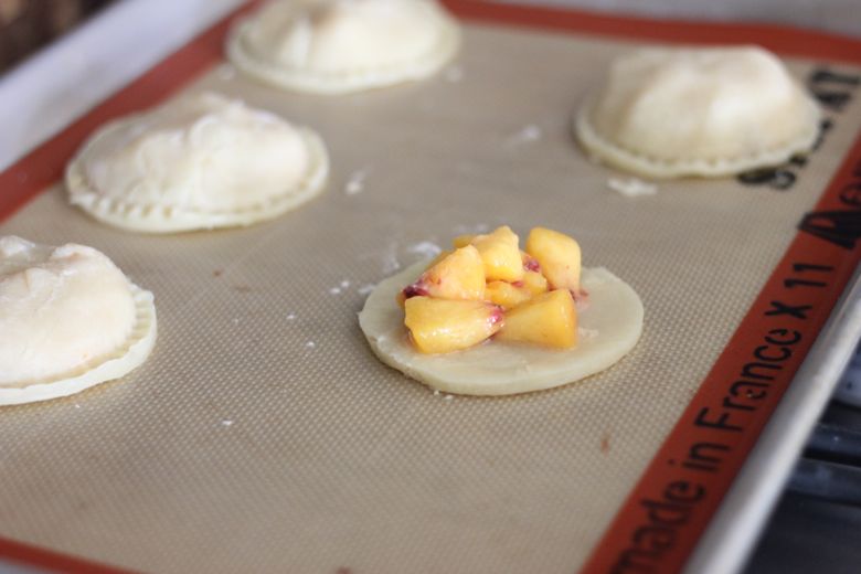 Peach Hand Pies on a Silpat lined baking sheet before baking.