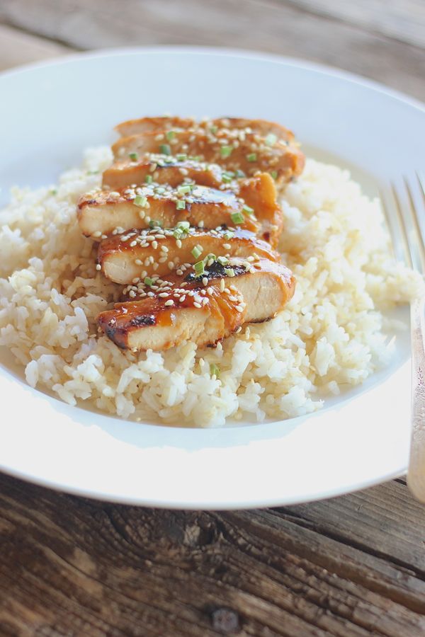Homemade Teriyaki Chicken sliced and served over rice on a plate with a fork.  