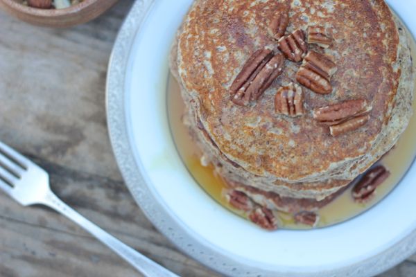 Healthy Pumpkin Pie Spice Oatmeal Flax Pancakes stacked and topped with pecans and maple syrup.  