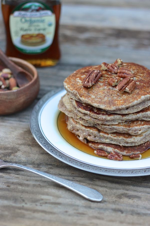 Healthy Pumpkin Pie Spice Oatmeal Flax Pancakes stacked and topped with pecans and maple syrup.