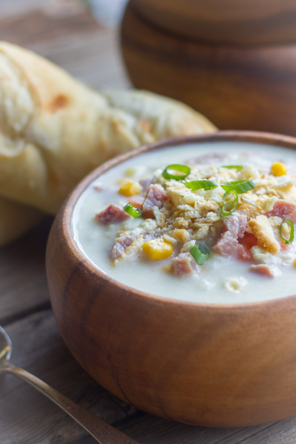 Creamy Potato Soup With Ham in a bowl with bread in the background.  