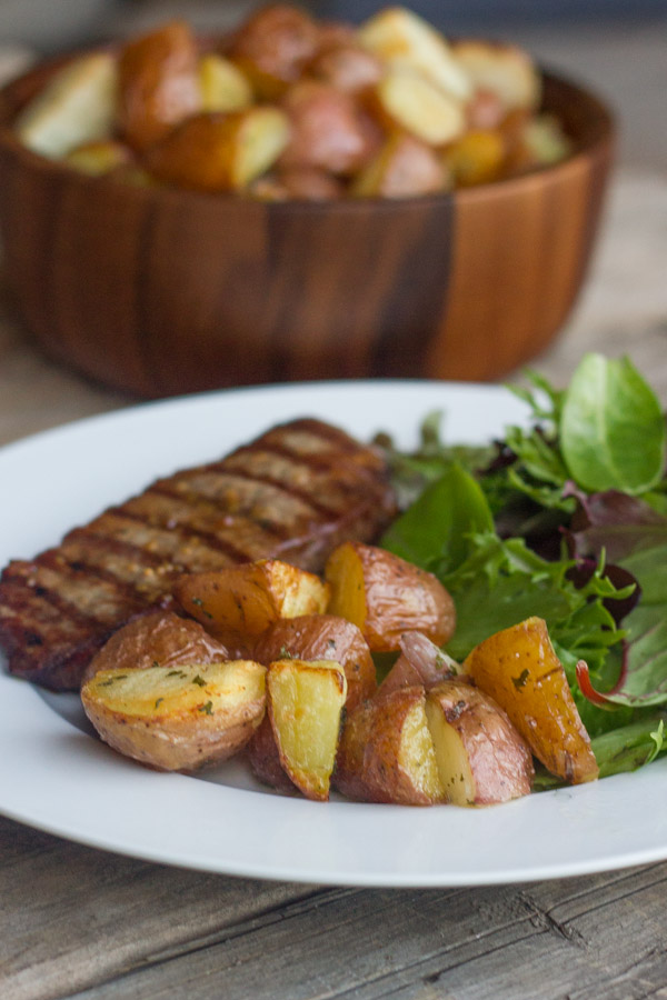 Roasted Red Potatoes on a dinner plate with steak and salad.  
