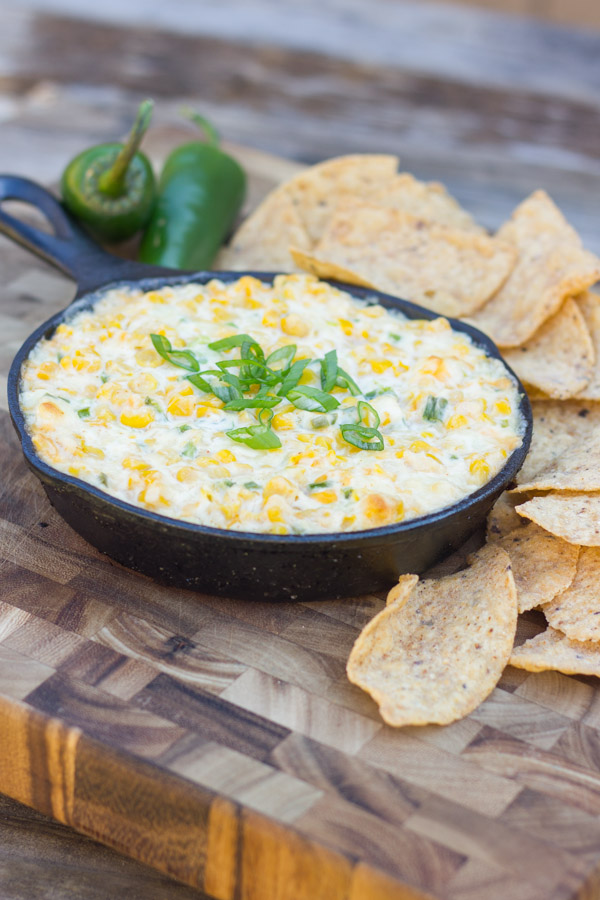 Hot Jalapeño Corn Dip in a cast iron skillet with jalapeños and tortilla chips around it.