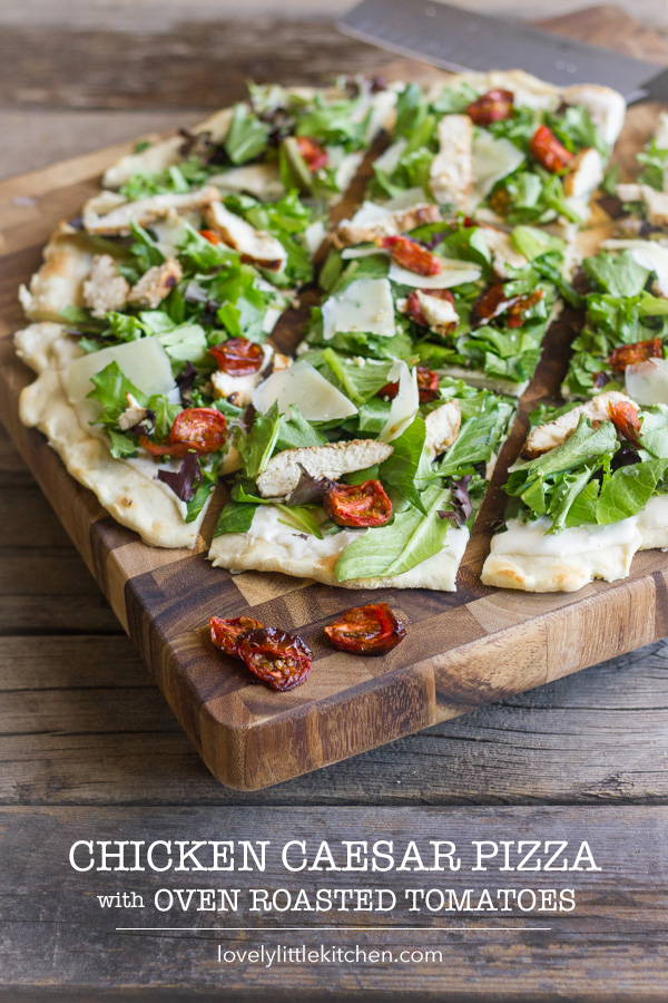 Chicken Caesar Pizza With Oven Roasted Tomatoes sliced on a cutting board.  