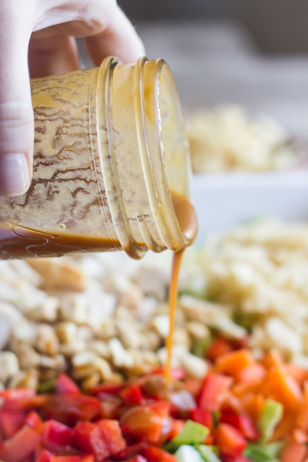 Chopped Chinese Chicken Salad with Sesame Peanut Dressing being poured on top.  