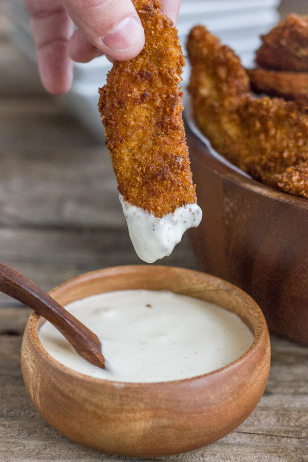 Extra Crispy Chicken Strip that has been dipped into a small bowl of dipping sauce. 