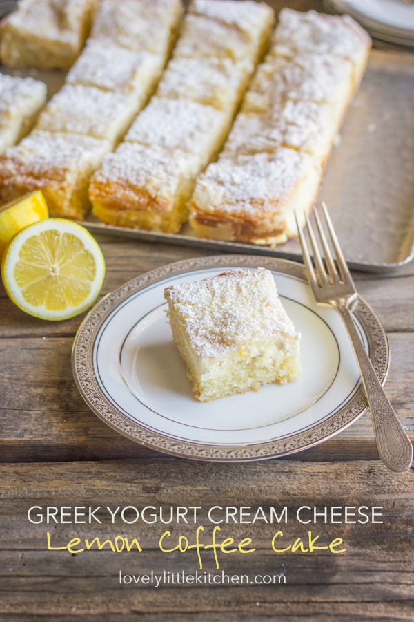 Greek Yogurt Cream Cheese Lemon Coffee Cake square piece on a plate with a fork, and the rest of the sliced cake on a serving tray in the background.  