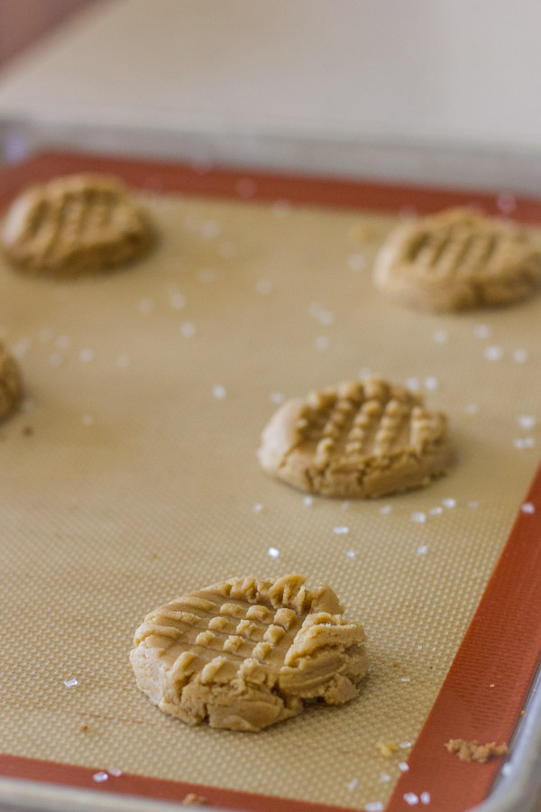 Brown Butter Peanut Butter Cookie dough on a Silpat lined backing sheet, pressed down with a crosshatch pattern and a sprinkle of sparkling sugar.
