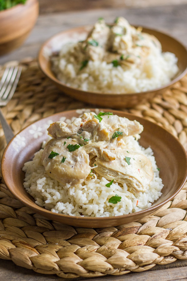 Easy Creamy Crockpot Chicken on top of a bowl of cooked rice. 