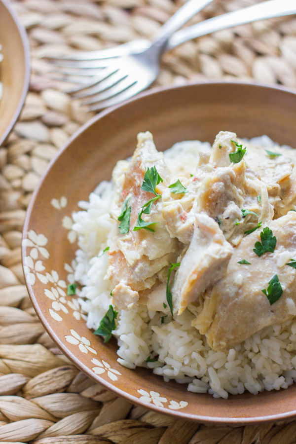 Easy Creamy Crockpot Chicken on top of a bowl of cooked rice. 