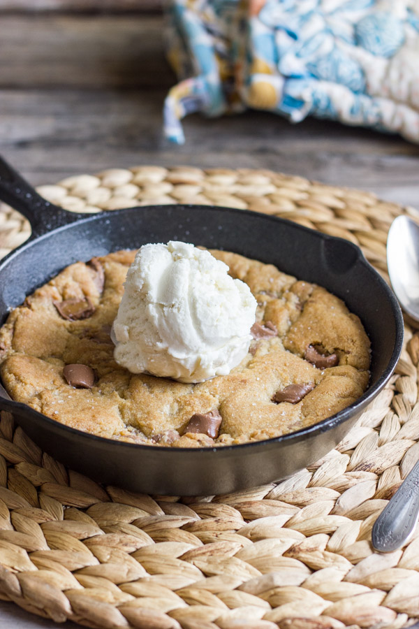 Salted Rolo Chip Pizookie in a small cast iron skillet, topped with a scoop of vanilla ice cream.