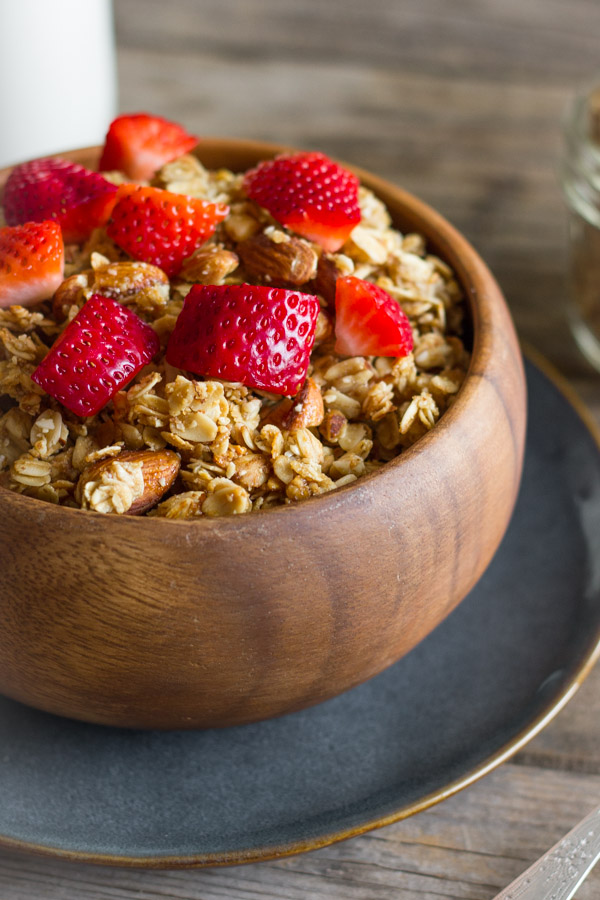 Homemade Coconut Oil Honey Almond Granola in a bowl with strawberry pieces on top.