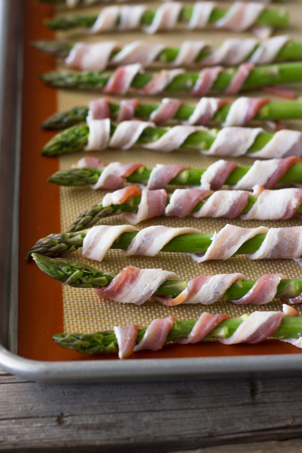 Bacon wrapped asparagus on a Silpat lined baking sheet.
