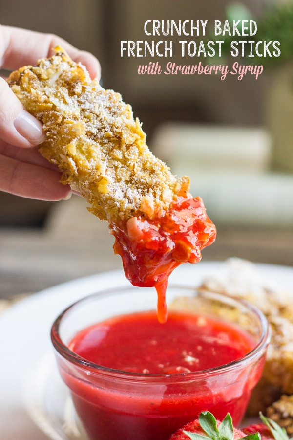 Crunchy Baked French Toast Stick being dipped into a glass dish of Strawberry Syrup.  