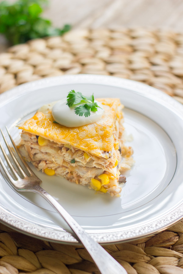 Southwestern Chicken Taco Pie slice topped with sour cream and cilantro, on a plate with a fork. 
