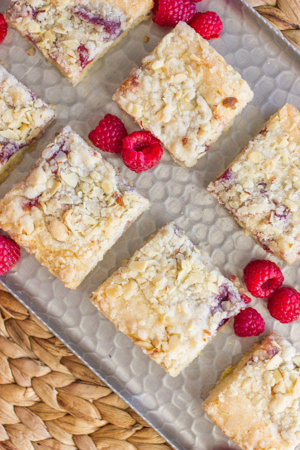 Raspberry Almond Crumb Bar squares on a serving platter with fresh raspberries.  