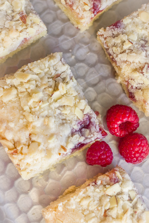 Raspberry Almond Crumb Bar squares on a serving platter with fresh raspberries.  