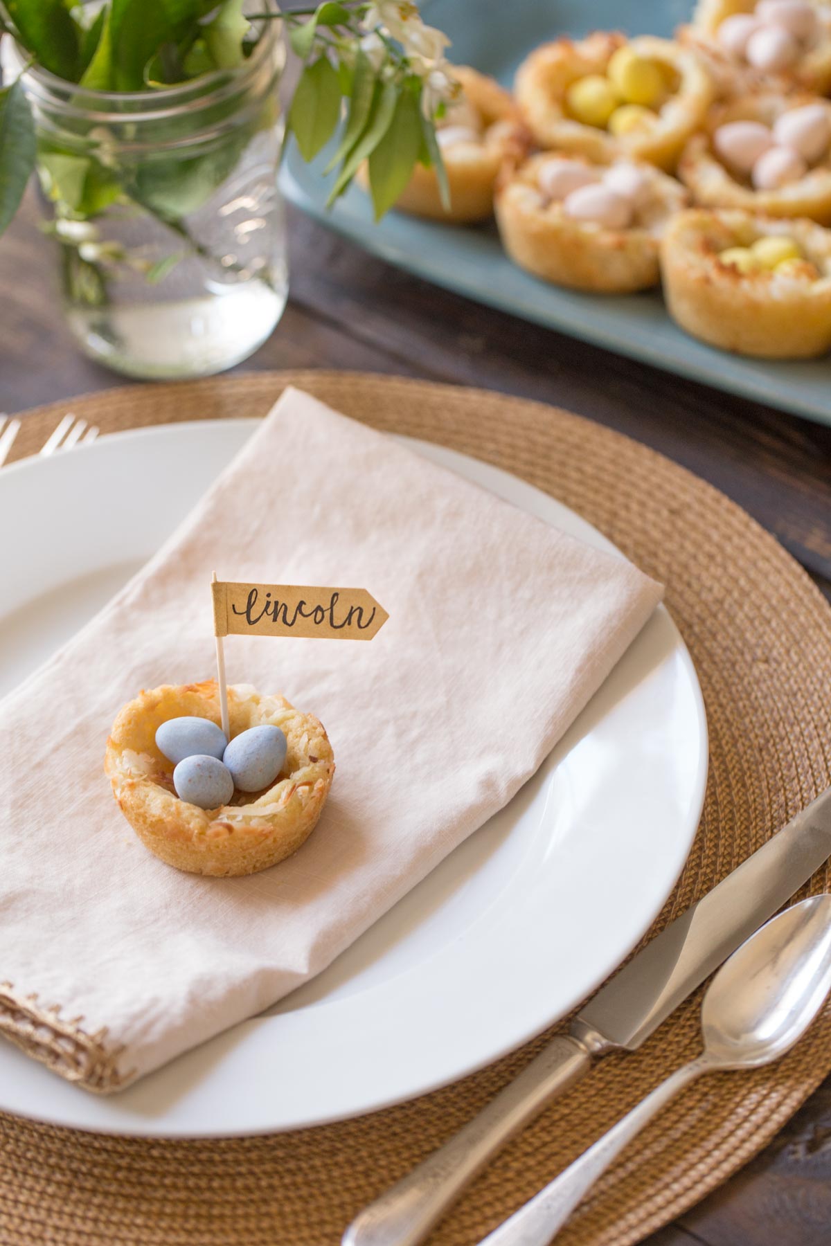 Sugar Cookie Easter Egg Nest with a name flag, sitting on top of a folded napkin on a place setting.  