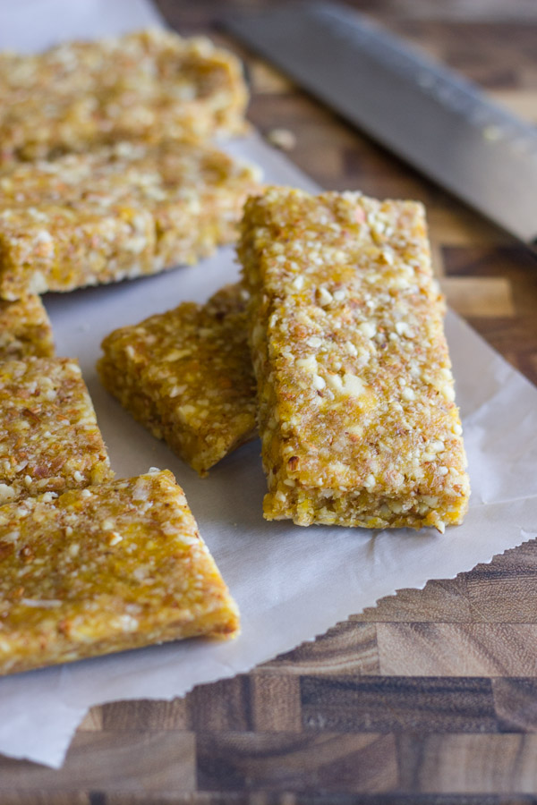 No Bake Apricot Almond Bars on parchment paper on top of a cutting bard with a knife.  