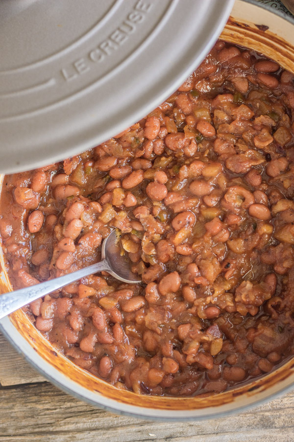 Sweet And Spicy BBQ Baked Beans in a Le Creuset French Oven with a spoon in it.  