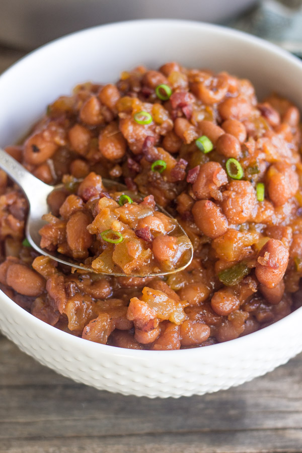 Sweet And Spicy BBQ Baked Beans in a bowl with a spoon in it.   