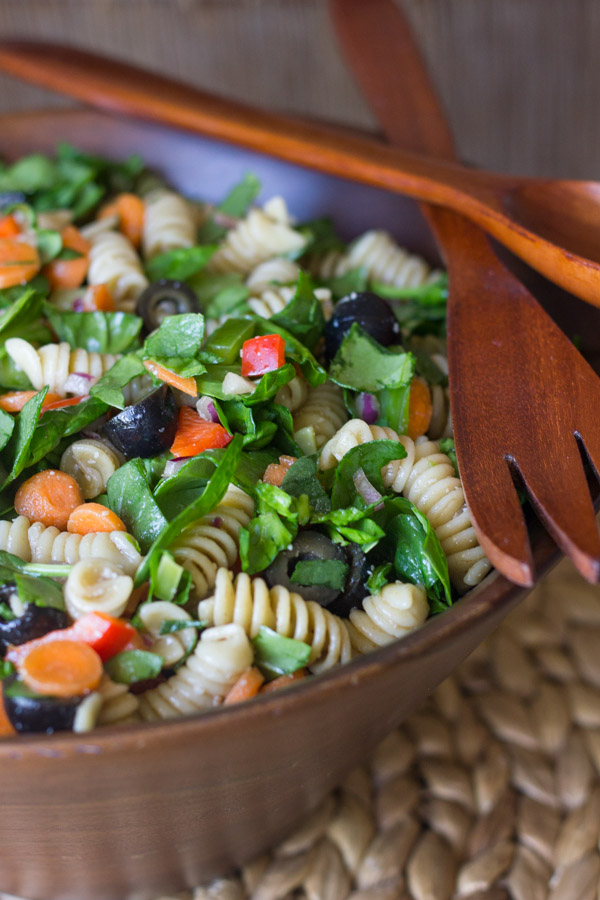 Chopped Spinach and Pasta Salad With Balsamic Vinaigrette in a large wooden bowl, with wooden serving utensils on top.  