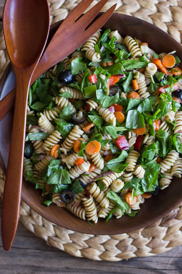 Chopped Spinach and Pasta Salad With Balsamic Vinaigrette in a large wooden bowl, with wooden serving utensils on top.  