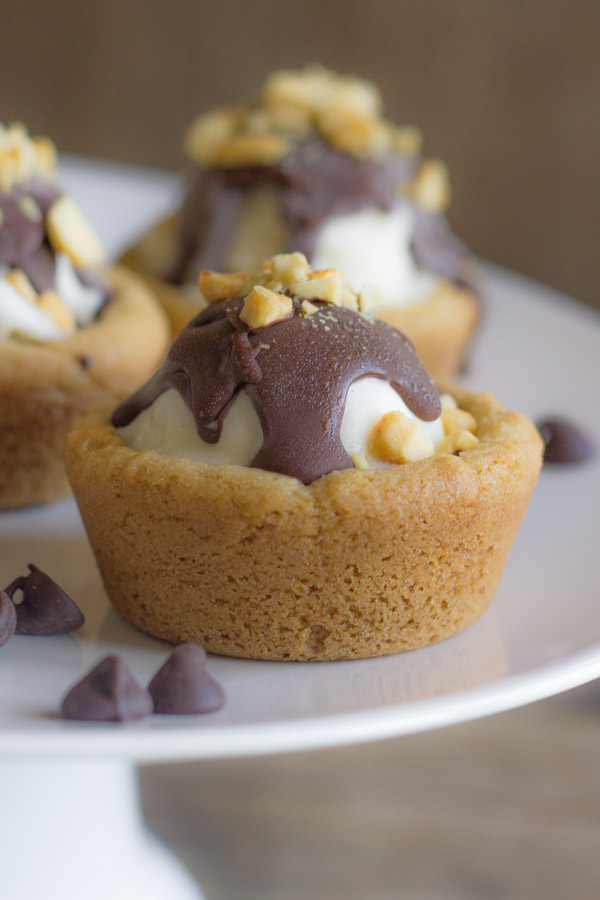 Ice Cream Sundae Cookie Cups on a cake stand with chocolate chips around them.  