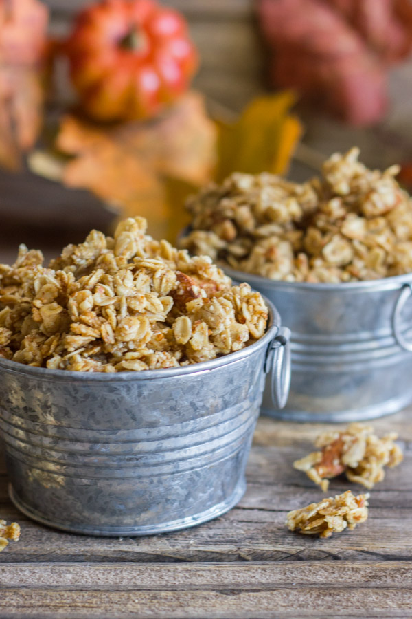 Pumpkin Pie Spice Coconut Oil Granola in two mini galvanized buckets, with some granola clusters next to the buckets and fall decorations in the background.  