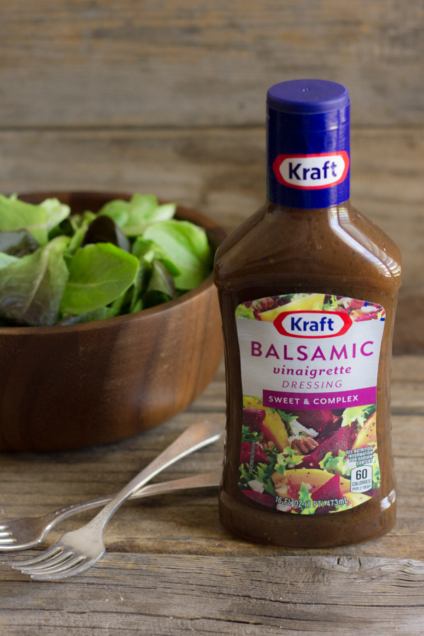 Kraft Balsamic Vinaigrette Dressing bottle, with a bowl of baby greens and two forks next to it.  
