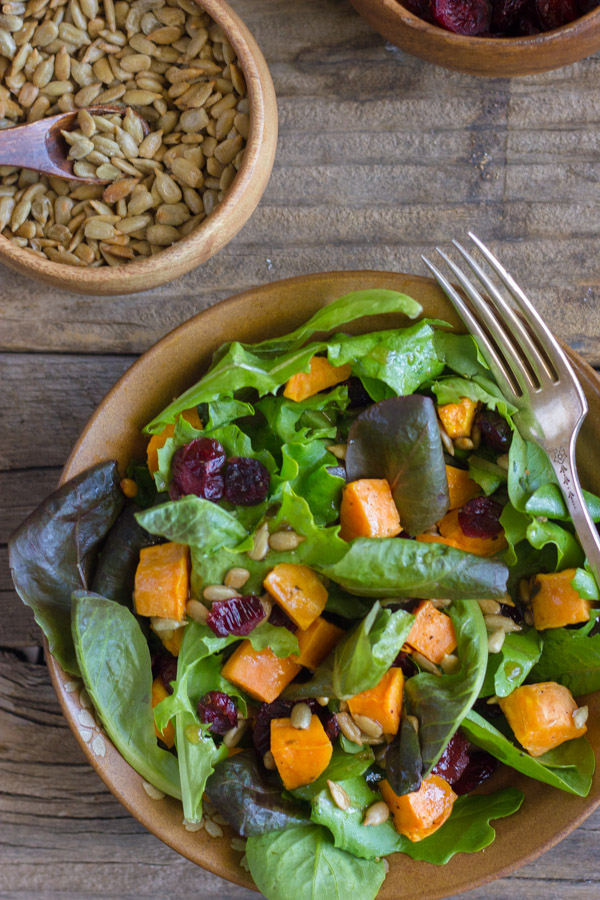 Roasted Sweet Potato Salad on a plate with a fork, with a small bowl of sunflower seeds next to it.  