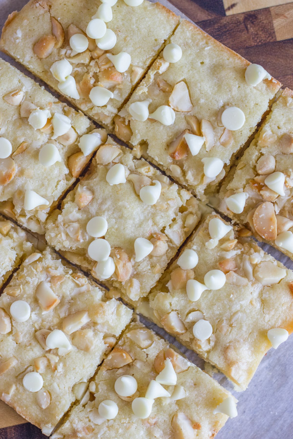 White Chocolate Macadamia Nut Bars cut into squares on a cutting board.  