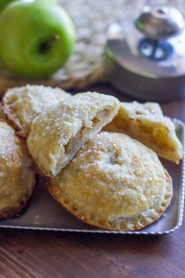 Apple Hand Pies on a serving platter, with one of the Apple Hand Pies cut in half.