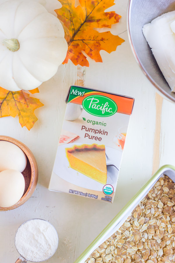 A box of Pacific Foods Organic Pumpkin Puree, surrounded by other ingredients for the Pumpkin Pie Cheesecake Bars. 