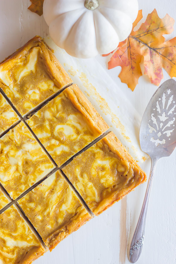 Pumpkin Pie Cheesecake Bars cut into squares, with a serving utensil next to them.  