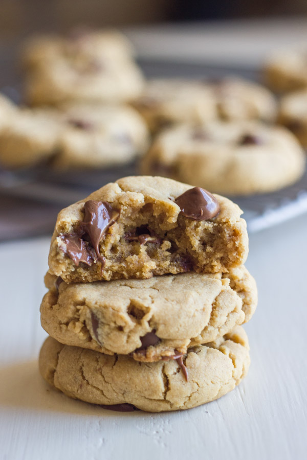 Peanut Butter Cookies With Peanut Butter Filled Chocolate Chips stacked in a pile of three, with the top one being a half of a cookie.  