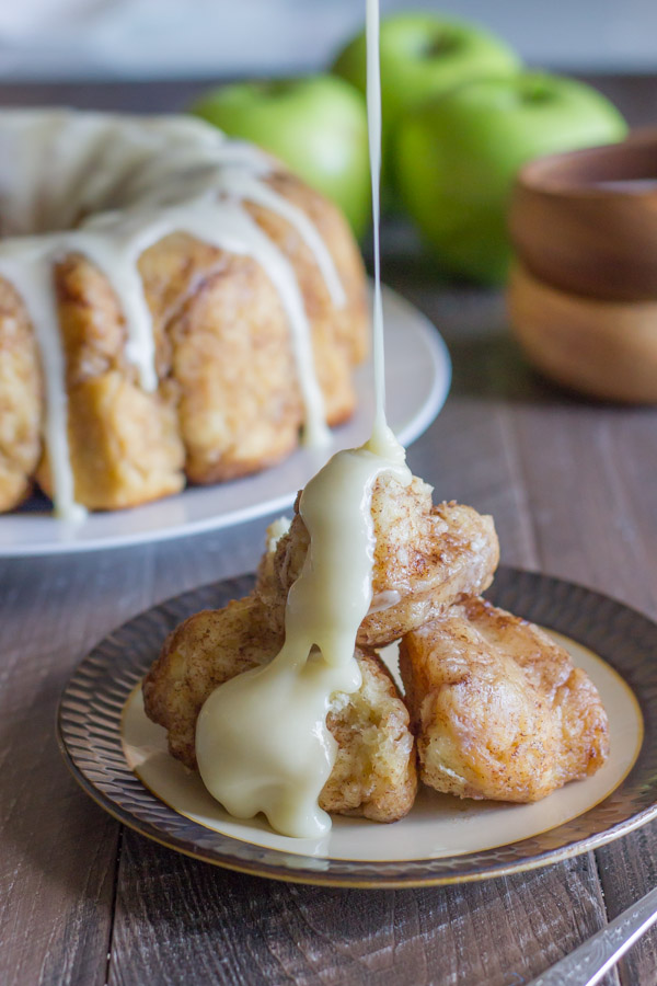 Apple Cinnamon Pull Apart Bread serving on a plate with Apple Cider Glaze being poured on top.  