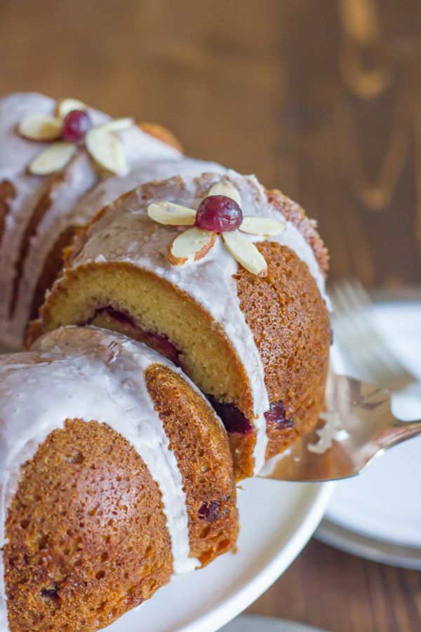 Cranberry Almond Greek Yogurt Cake slice on a serving utensil, being pulled away from the rest of the cake.  