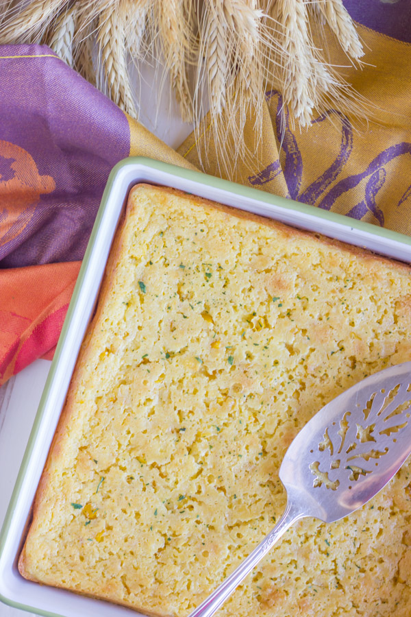 Easy Corn Soufflé in a square baking dish with a serving spoon.