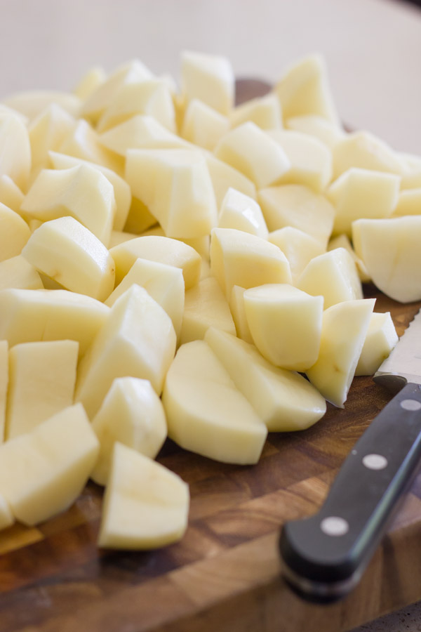 Chopped potatoes on a cutting board with a knife.