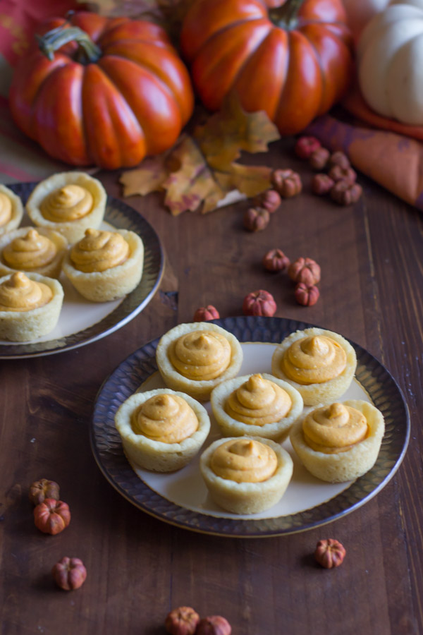 Two plates of Easy Mini Pumpkin Pie Tarts, with fall decorations around them.  