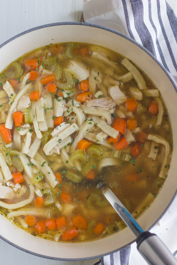 Homemade Chicken Noodle Soup in a large pot with a serving spoon.  