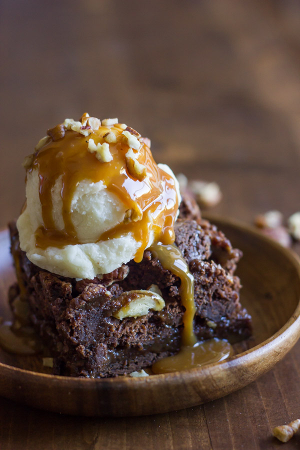 Copycat Zupas Rockslide Brownie on a plate, topped with a scoop of ice cream, caramel sauce and chopped pecans. 