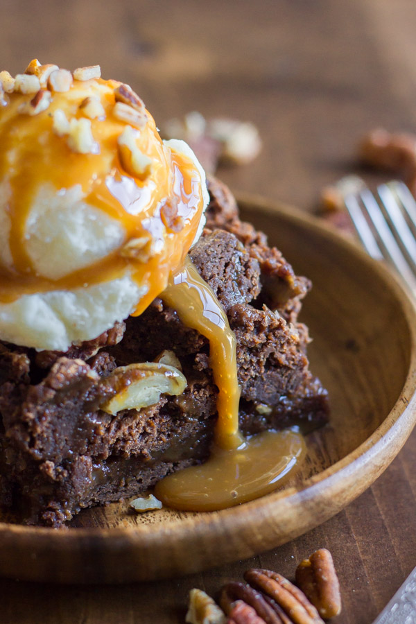 Copycat Zupas Rockslide Brownie on a plate, topped with a scoop of ice cream, caramel sauce and chopped pecans. 