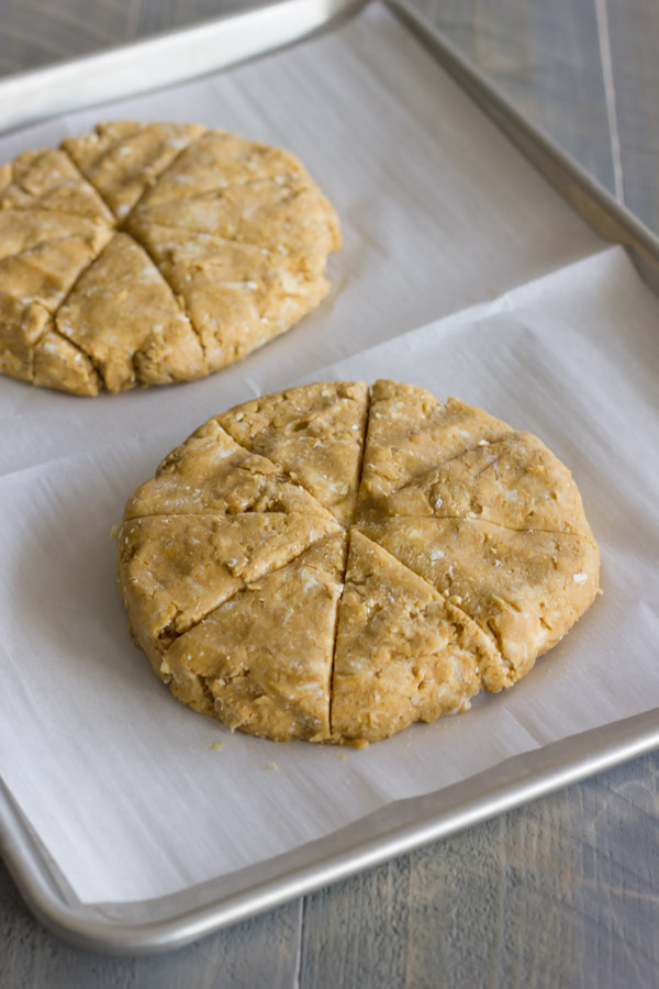 Gingerbread Oat Scones dough in two discs, cut in wedges on a parchment paper lined baking sheet.  