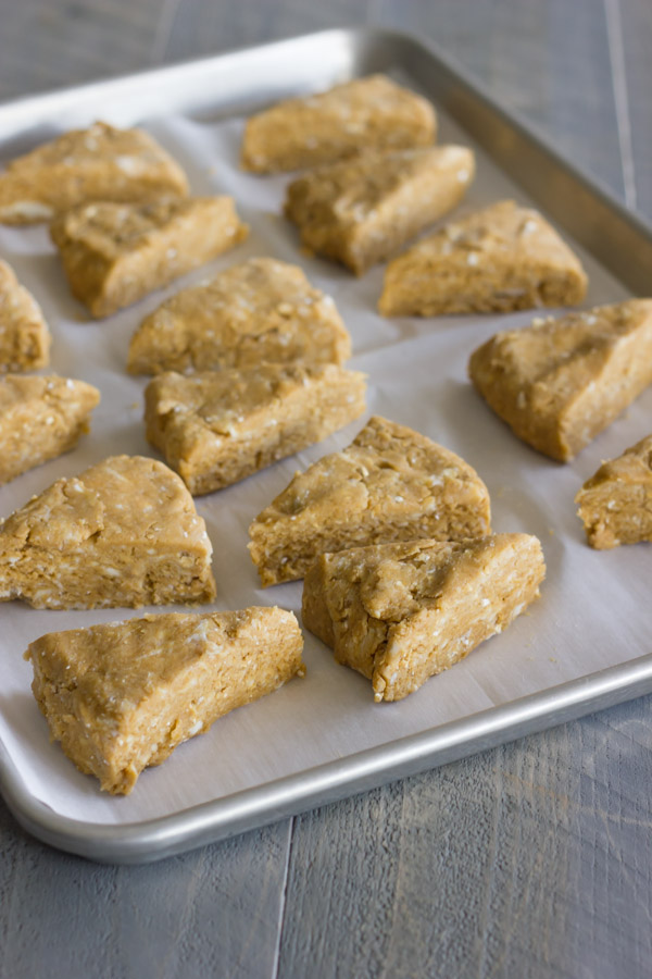 Gingerbread Oat Scones dough wedges arranged on a parchment paper lined baking sheet.  