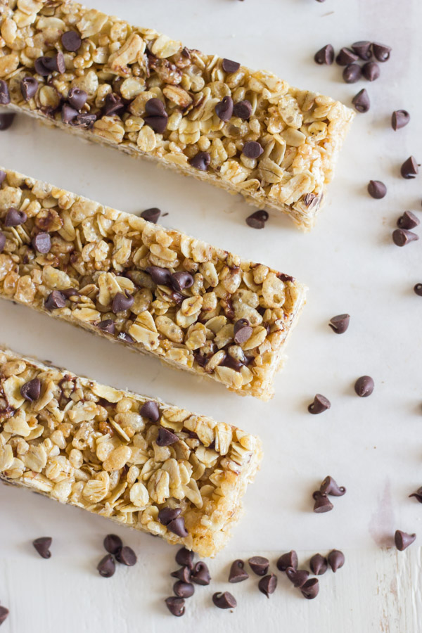 Three Copycat Quaker Chewy Chocolate Chip Granola Bars next to each other with chocolate chips sprinkled around them. 